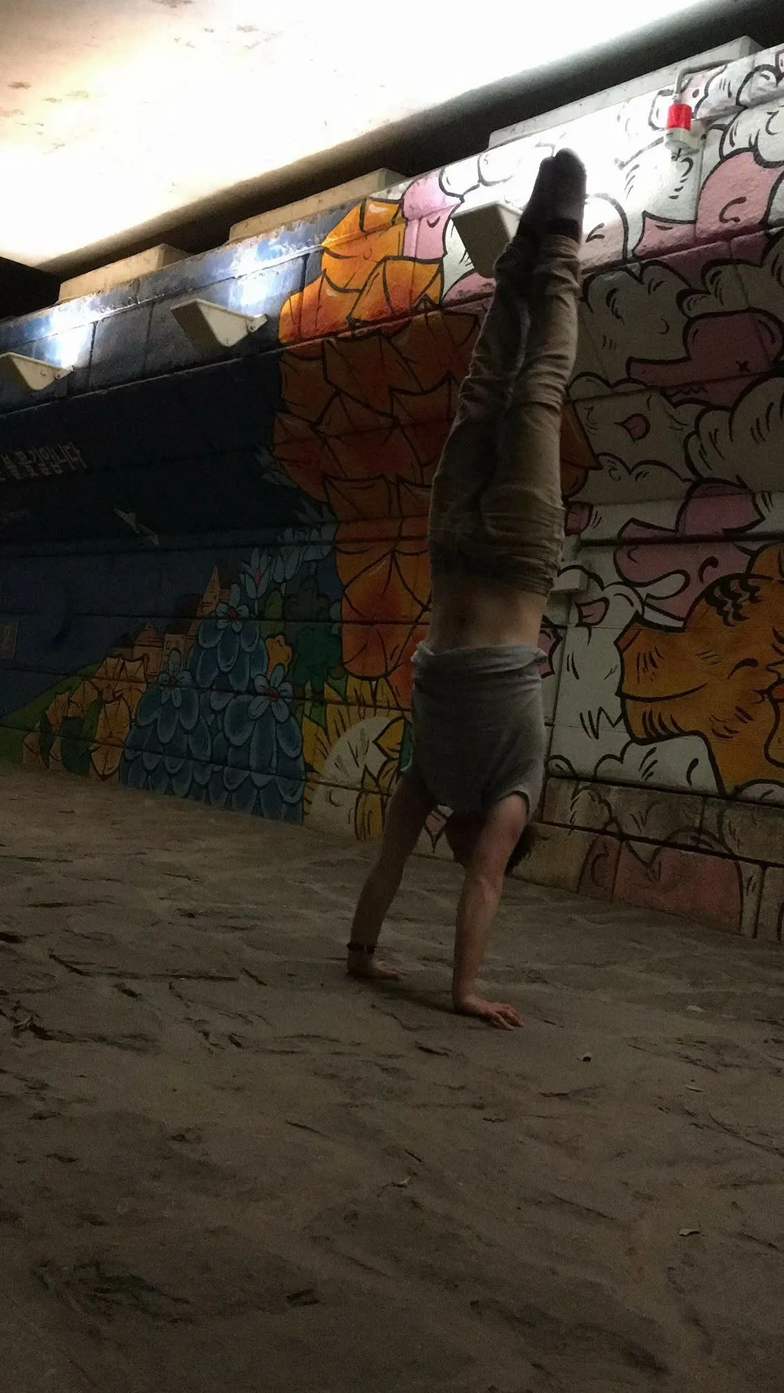 A full handstand against a mural in Seoul
