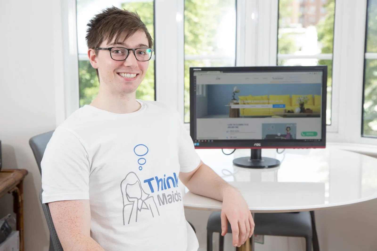 Chris in a Think Maids t-shirt beside the booking site